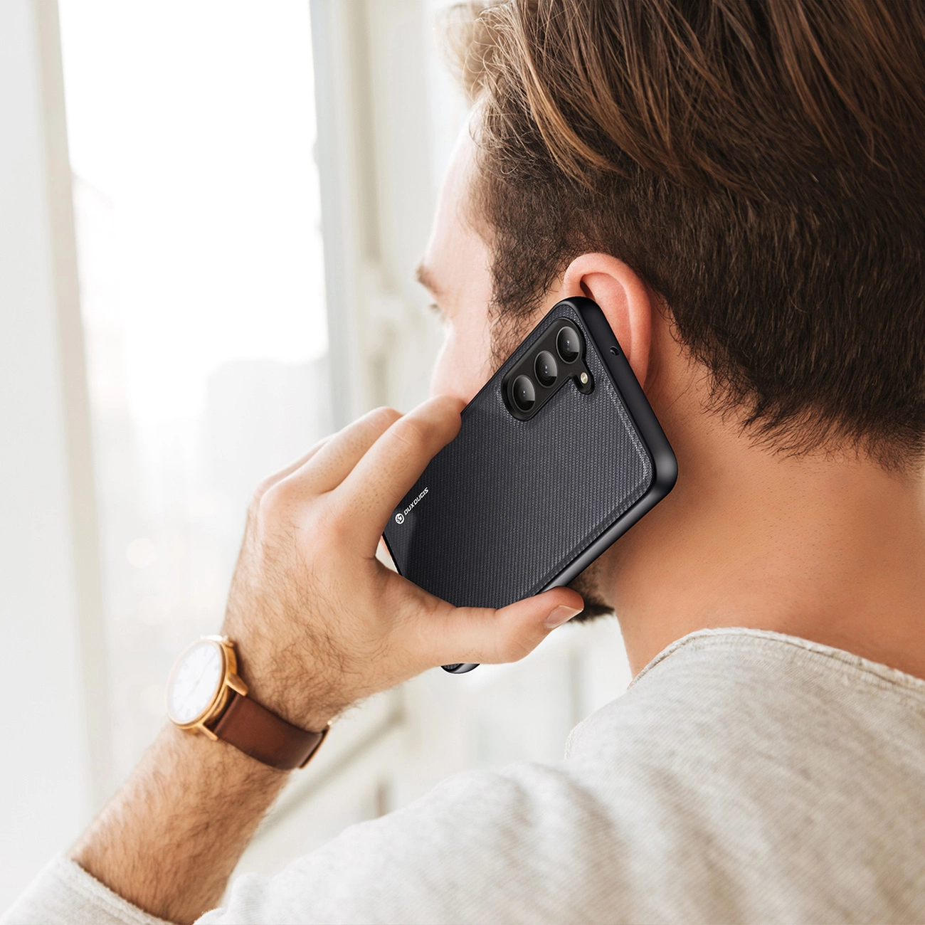 Un uomo con i capelli castani sta parlando al telefono nero.