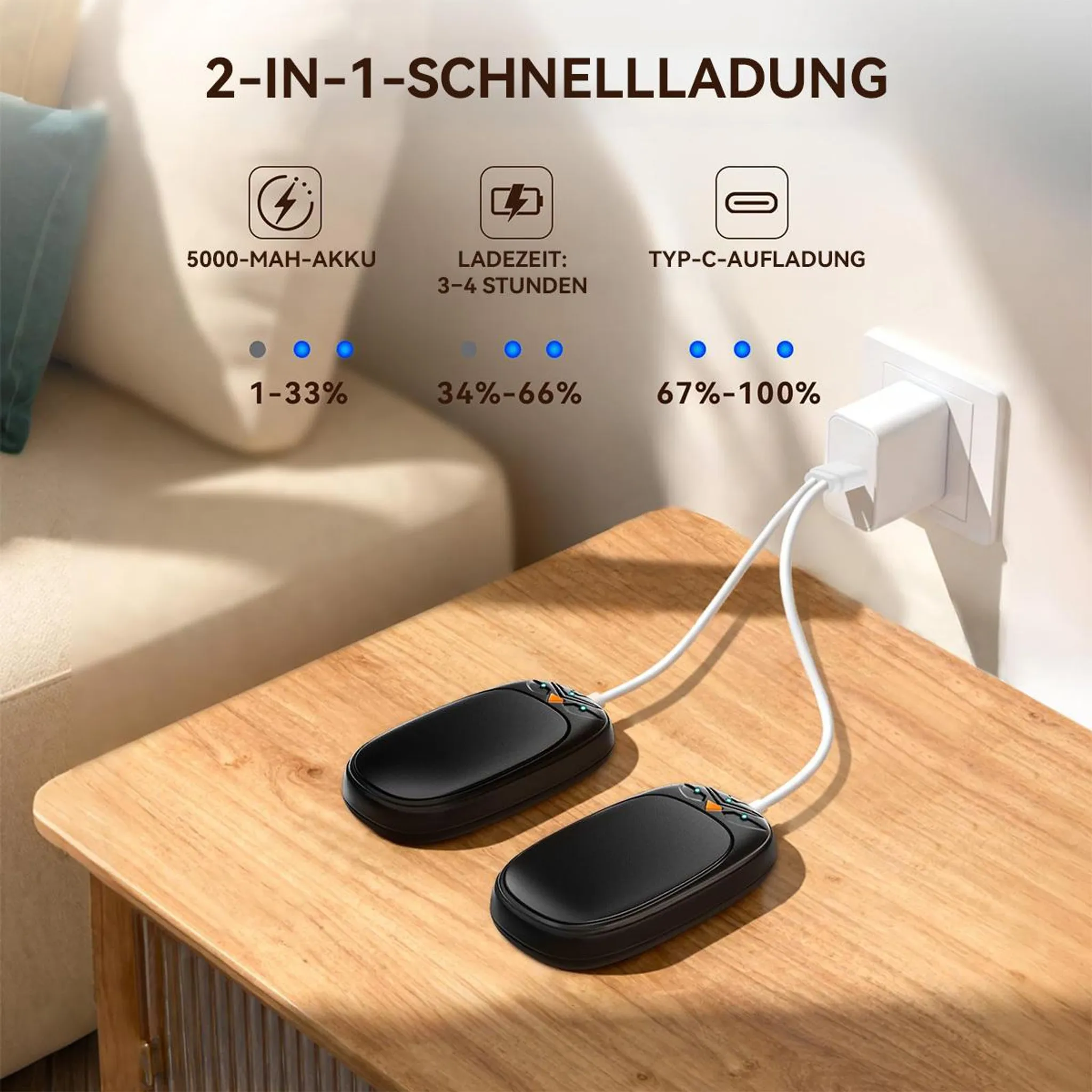 Zwei schwarze Handwärmer auf einem Holztisch, an eine Steckdose angeschlossen, mit Ladeinfos oben.