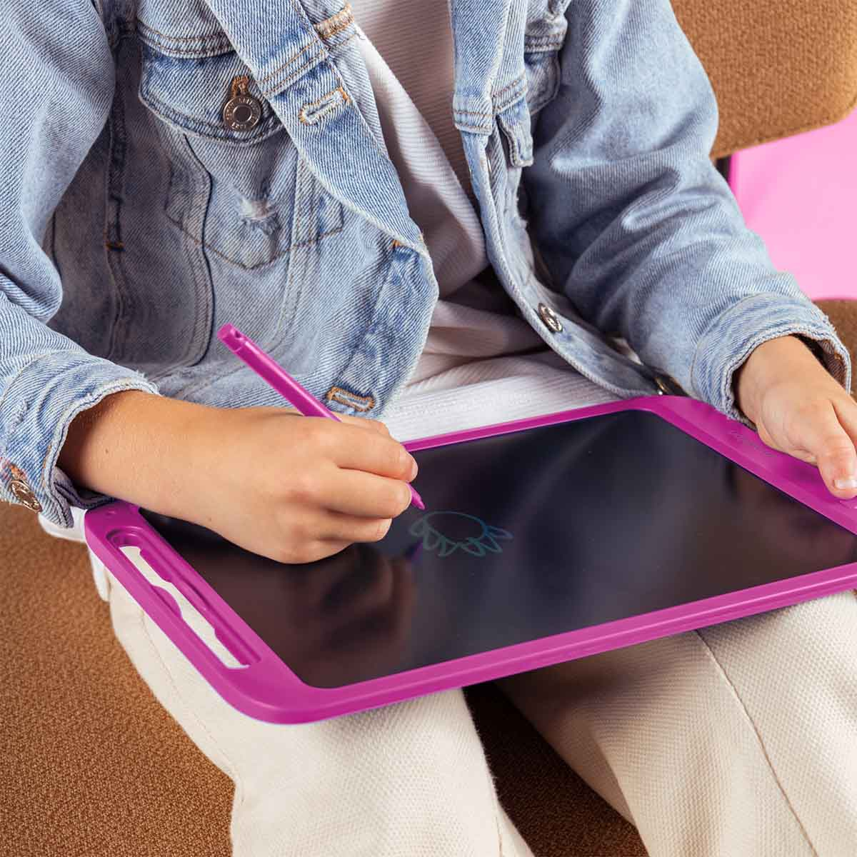 Un bambino con una giacca di jeans disegna su un tavoletta da disegno elettronica rosa.