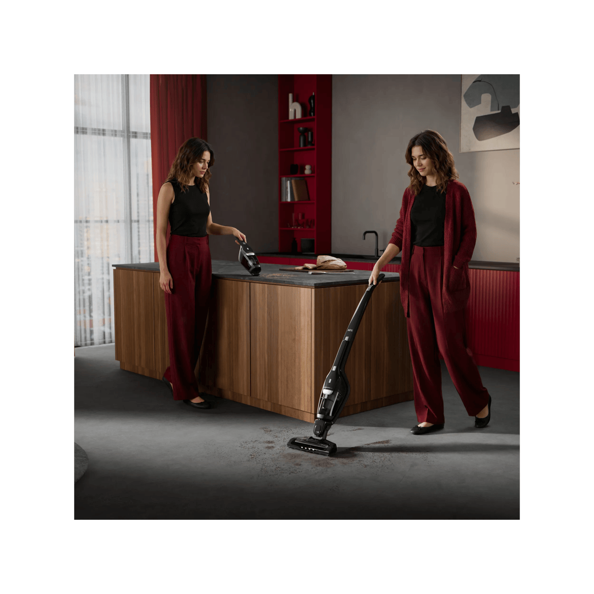 Una mujer con pantalones rojos usa una aspiradora escoba en una cocina moderna.