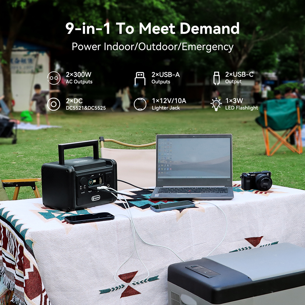 Una estación de energía portátil alimenta una laptop y un teléfono en una mesa al aire libre.