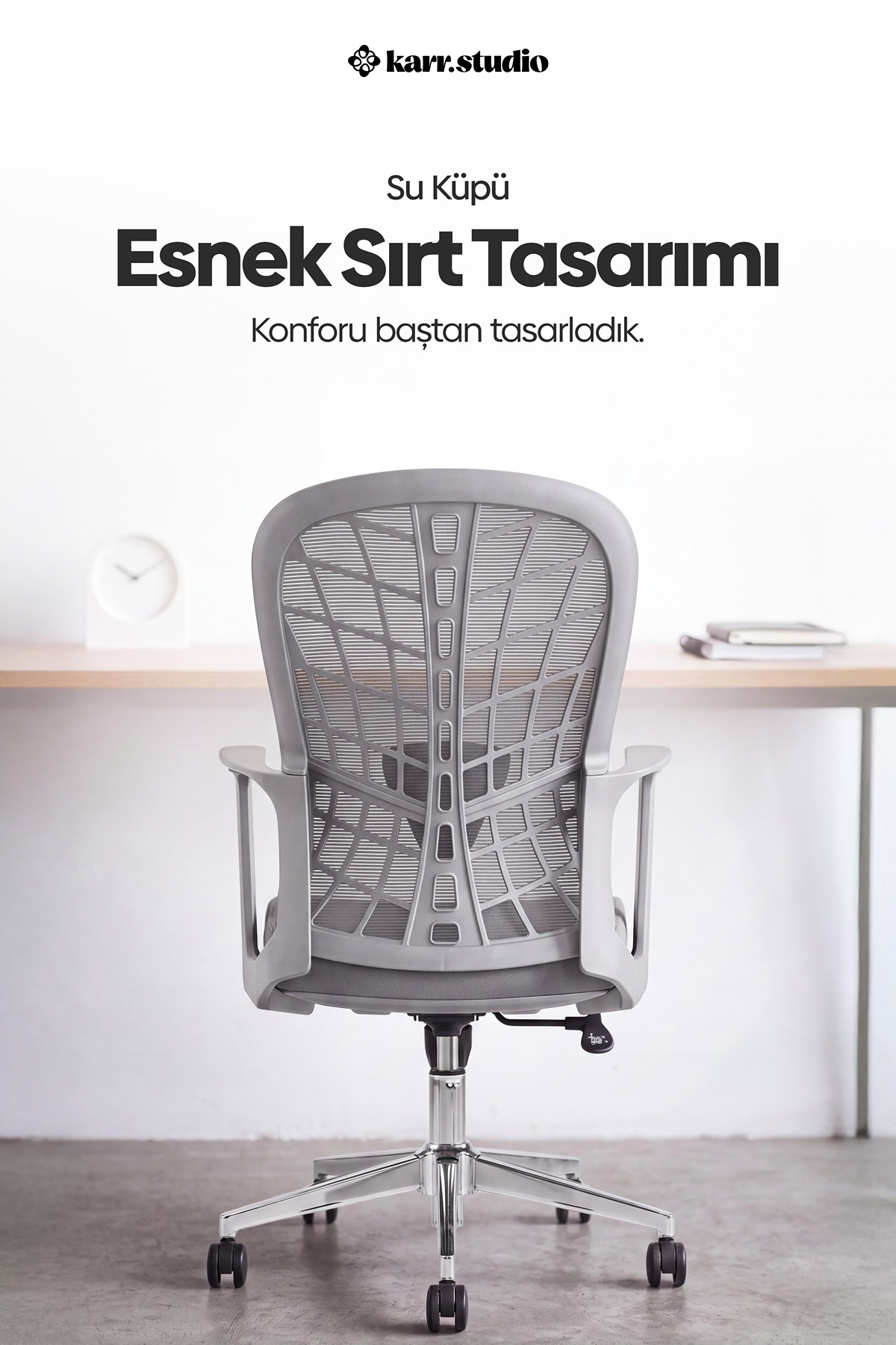 Açık renkli odada, masanın önünde duran file sırtlı gri ergonomik ofis koltuğu.