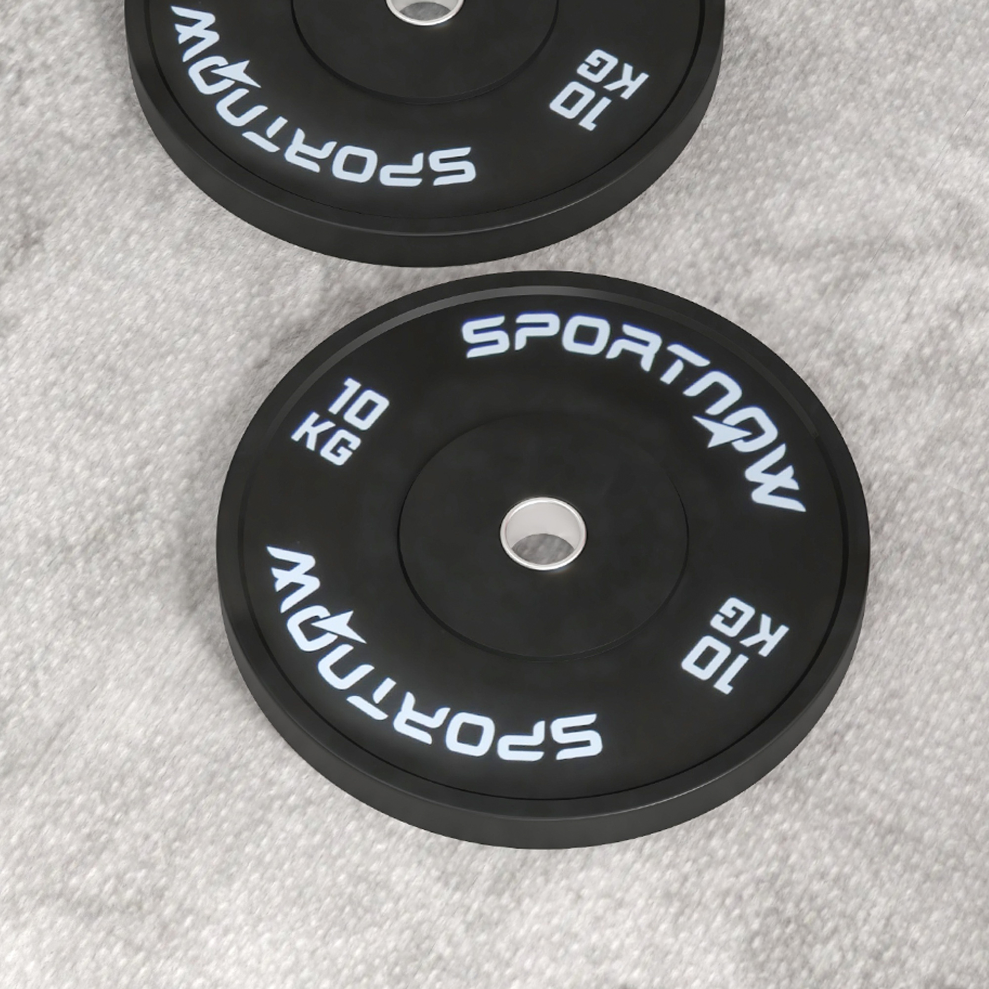 Dos discos de pesas negros de 10 kg con letras blancas descansan sobre una alfombra gris.