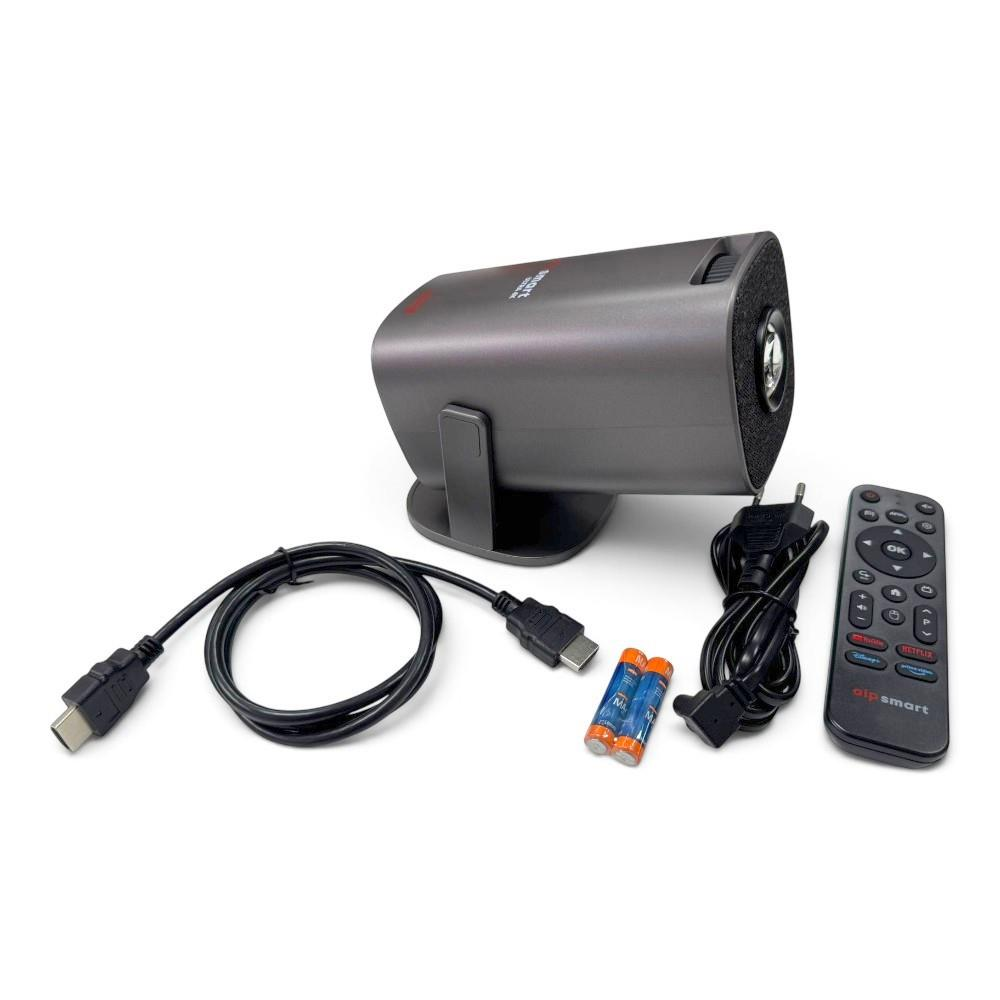 Stand üzerinde gri mini projektör, yanında HDMI kablosu, güç kablosu, piller ve bir uzaktan kumanda.