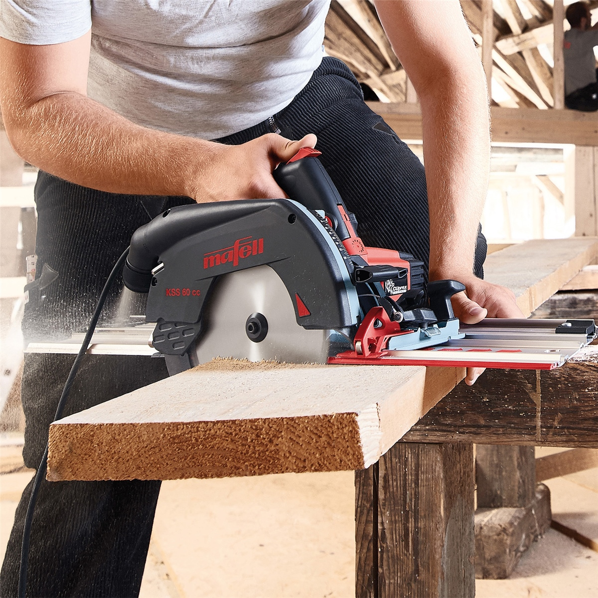 Ein Handwerker schneidet mit einer roten und schwarzen Mafell Handkreissäge ein Holzbrett auf einer Werkbank.