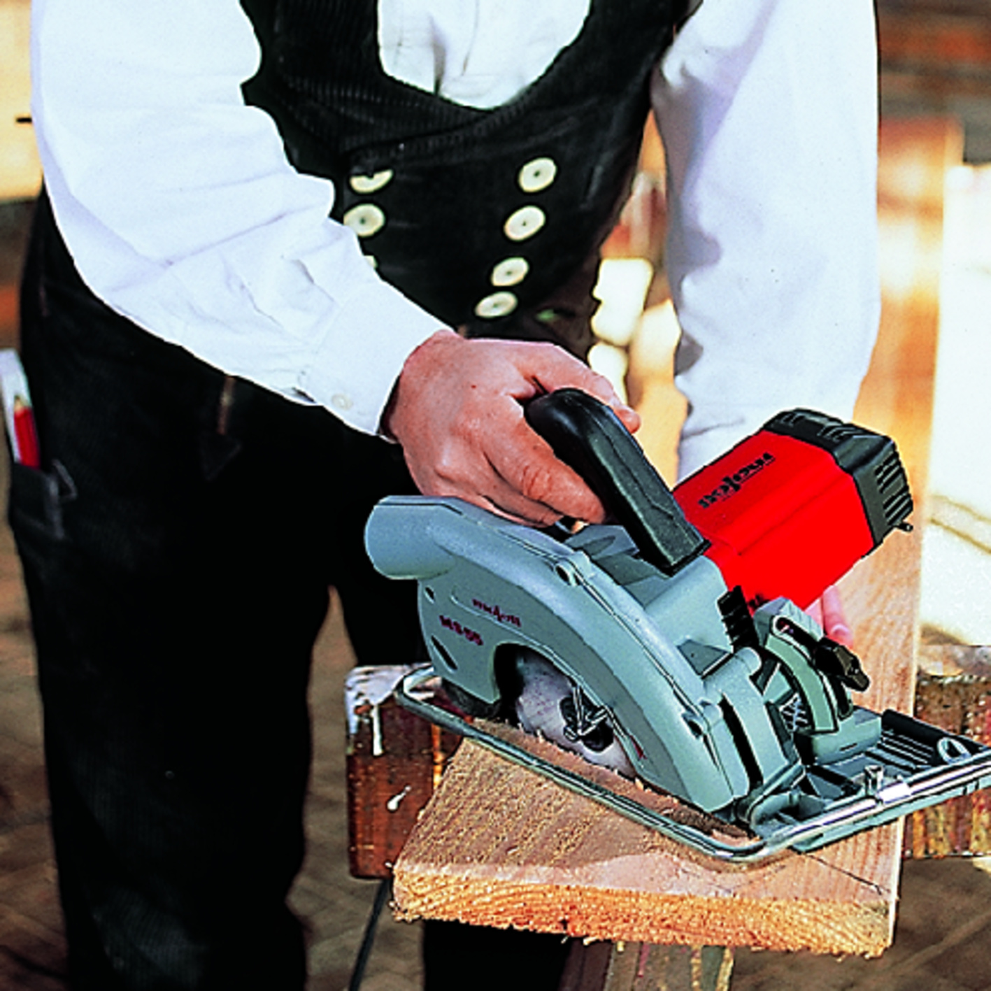 Handwerker sägt ein Holzbrett mit einer roten und grauen Handkreissäge.