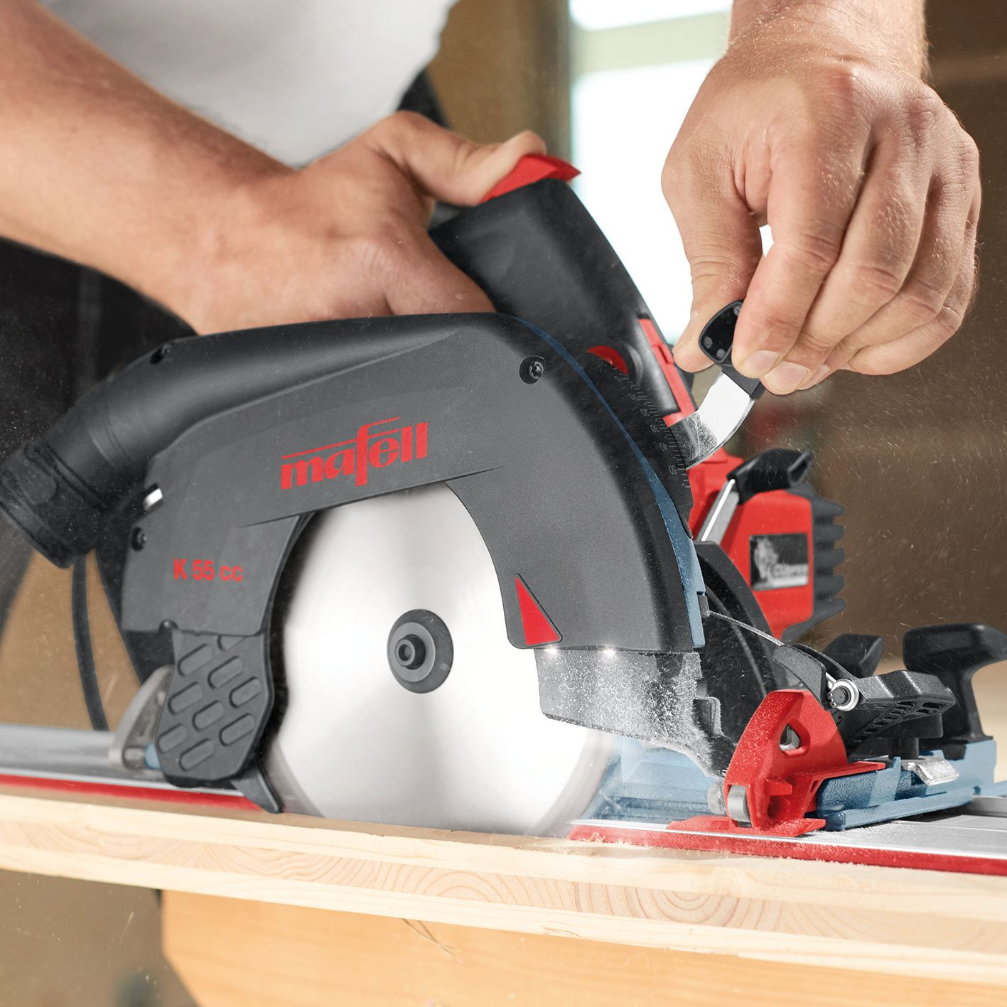 Ein Handwerker bedient eine rote und schwarze Mafell K 55 cc Kreissäge, die in Holz schneidet.