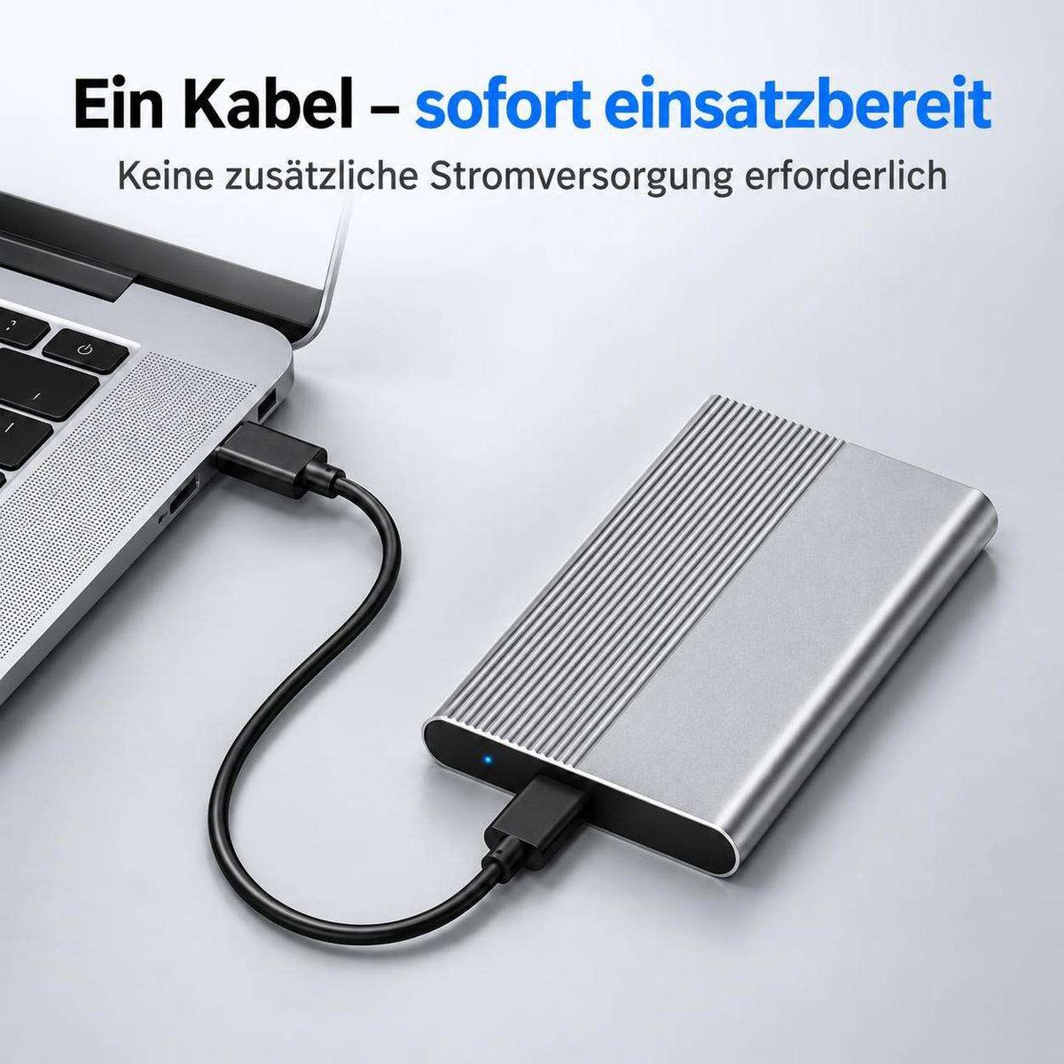 Silberne externe Festplatte, die über ein einzelnes schwarzes Kabel mit einem Laptop verbunden ist.