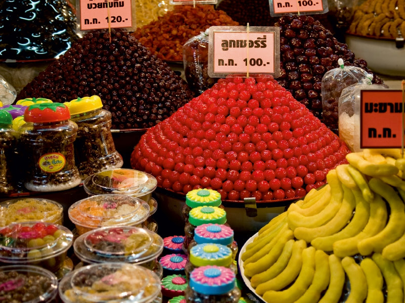 Stände mit Haufen von bunten kandierten Früchten, Süßigkeiten und Plastikgläsern auf einem Markt.