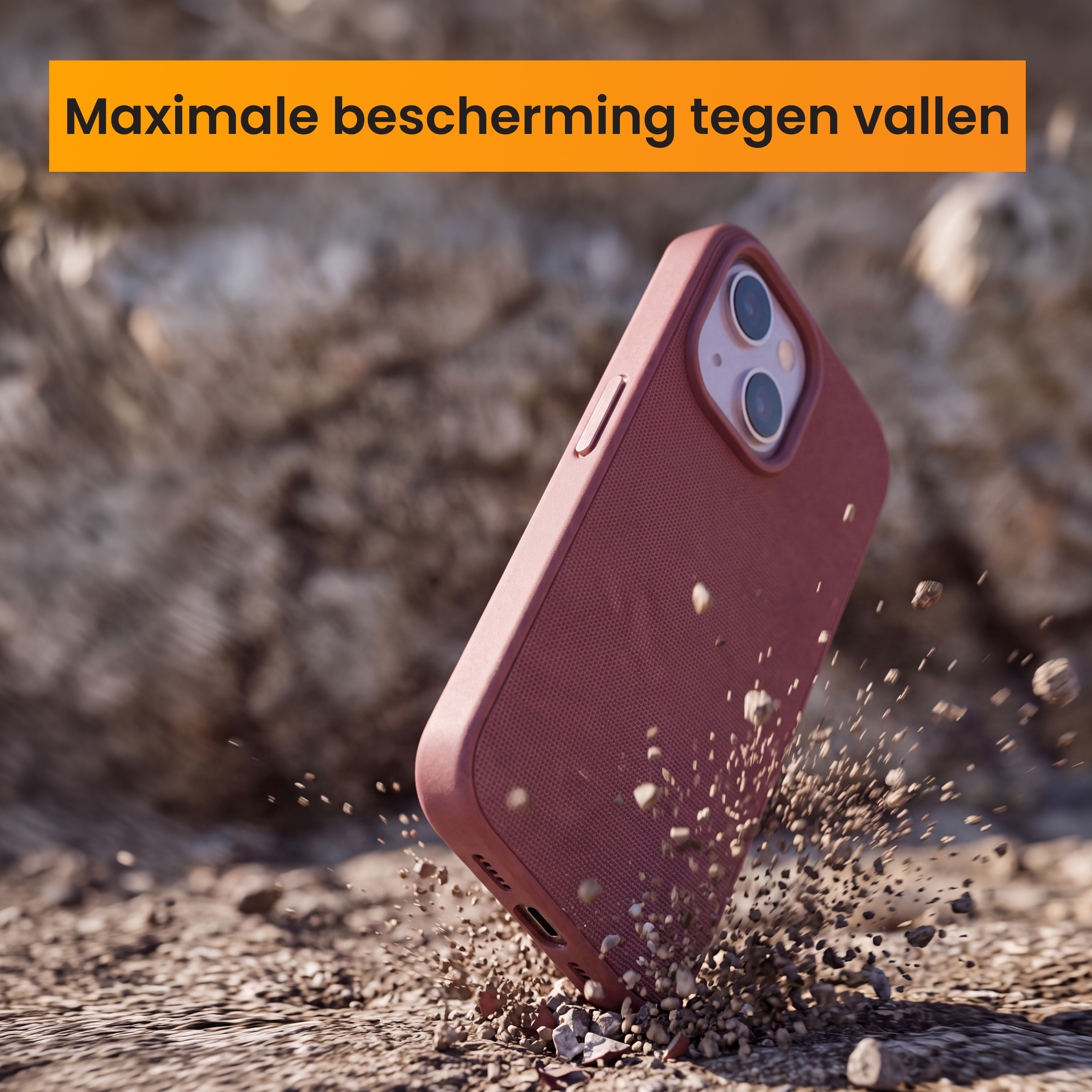 Een roze smartphone in een beschermhoes valt op zandgrond met opspattende steentjes.