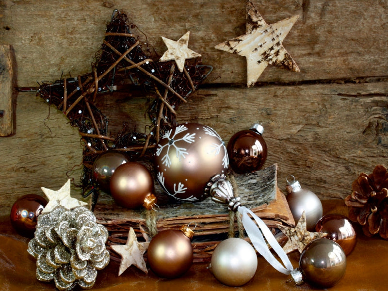 Rustikale Weihnachtsschmuckstücke mit braunen Kugeln, Holzbögen und Sternen auf Holz.