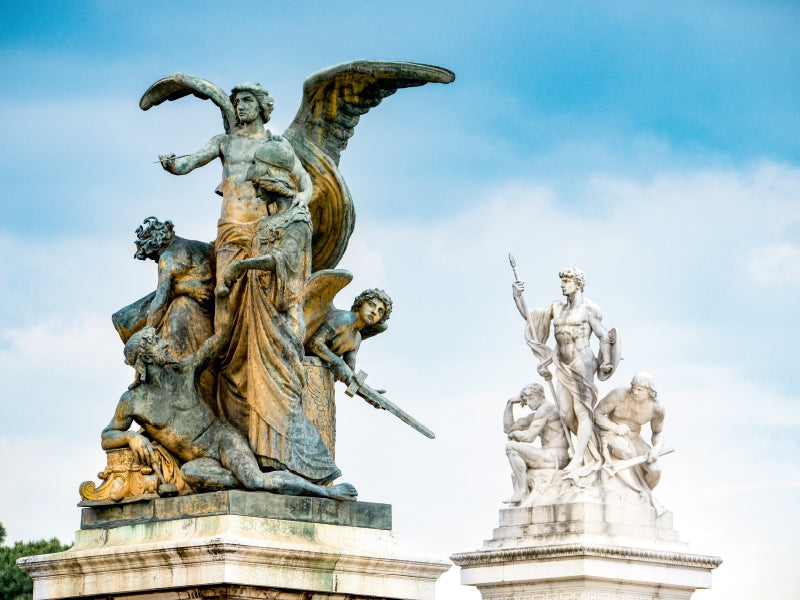 Bronzene und weiße Marmorstatuengruppen stehen vor einem blauen Himmel.