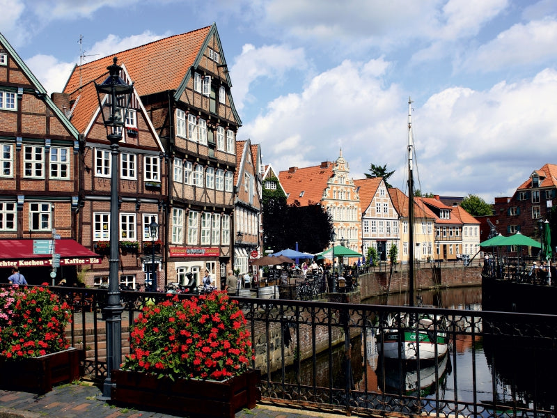 Historische Fachwerkhäuser an einem Flussufer in Deutschland mit roten Blumen im Vordergrund.