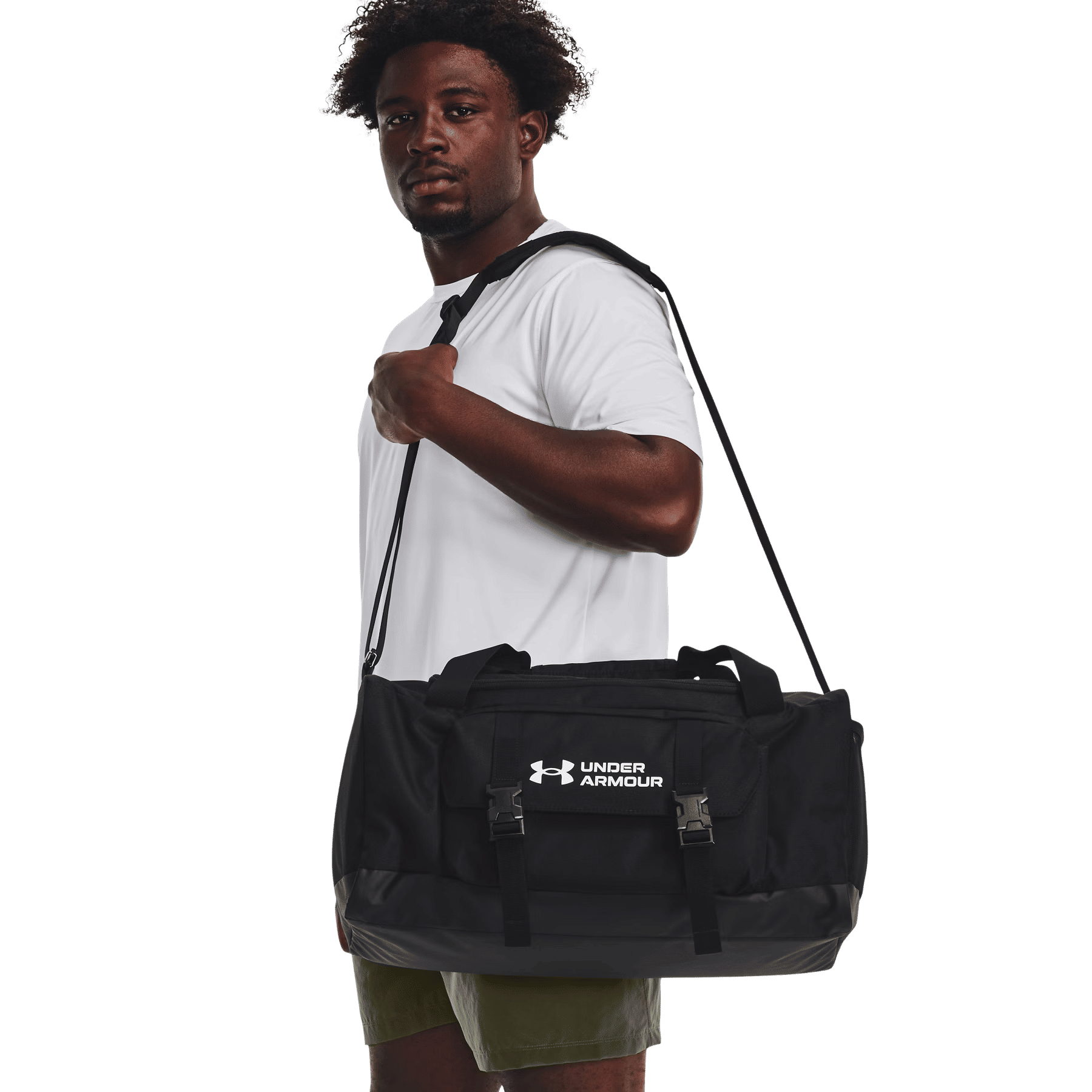 Un uomo con una maglietta bianca e pantaloncini verdi tiene la tracolla di una borsa sportiva nera Under Armour.