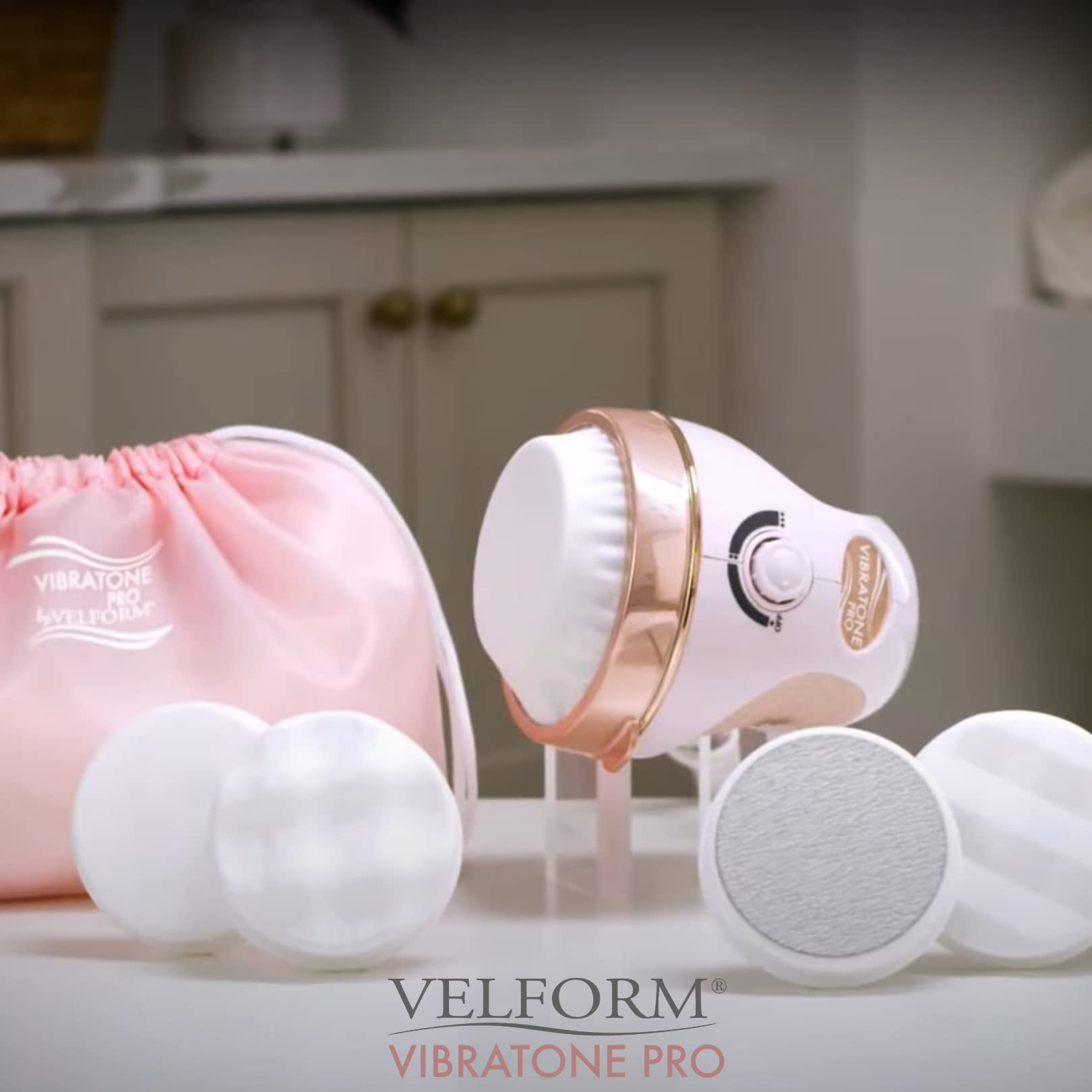 Un appareil Velform Vibratone Pro blanc et or rose avec accessoires et sac rose.