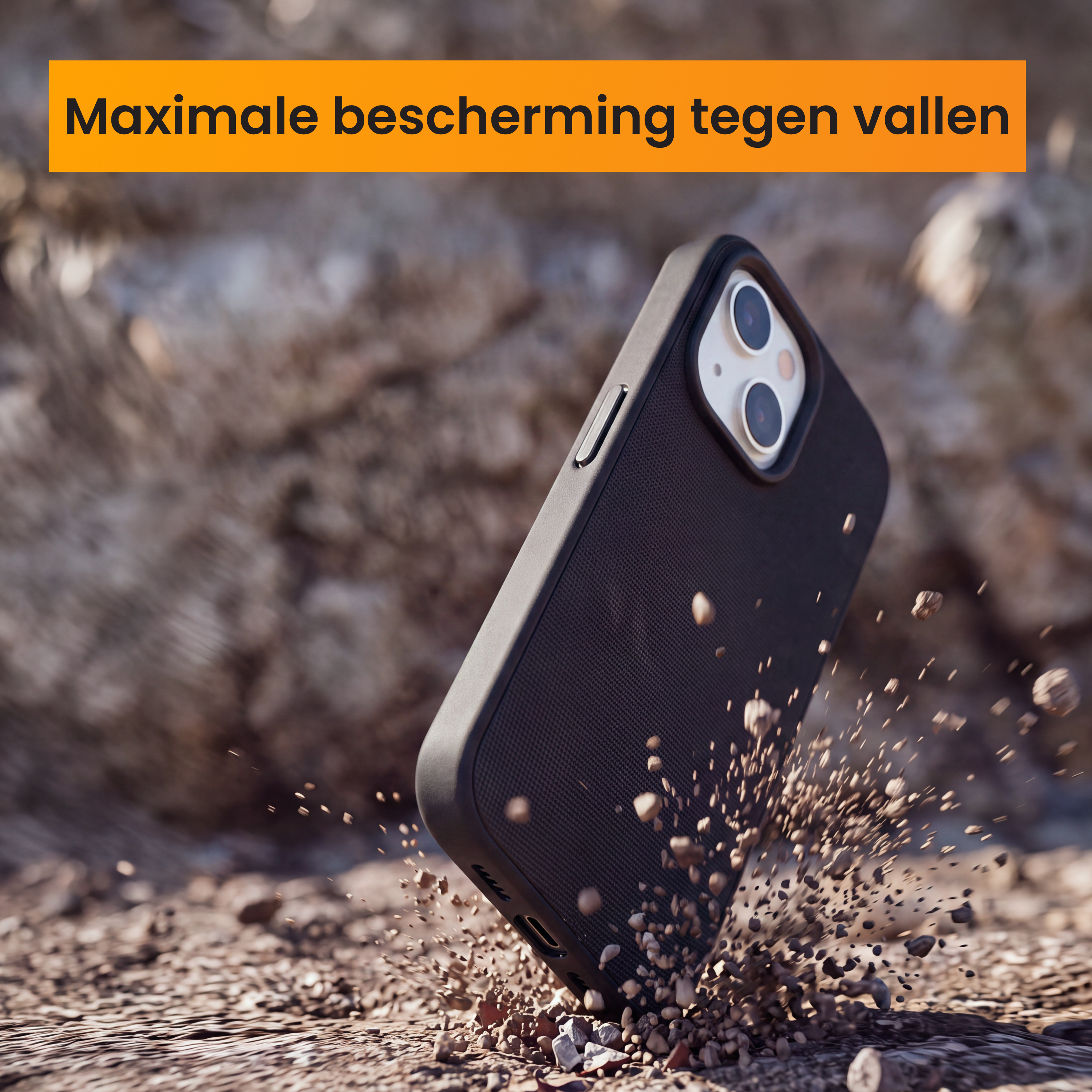 Een zwarte smartphone in een beschermhoes valt op rotsachtige grond en stuift grind op.