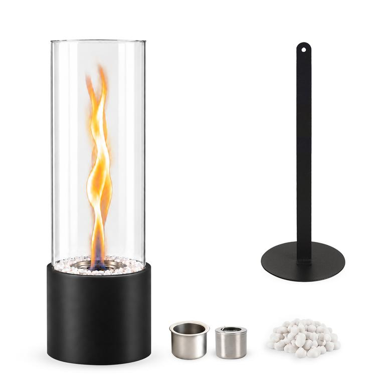 Ein zylindrischer Tischkamin mit Glasaufsatz, Flamme, Werkzeug, zwei Brennkammern und weißen Zierkieselsteinen.