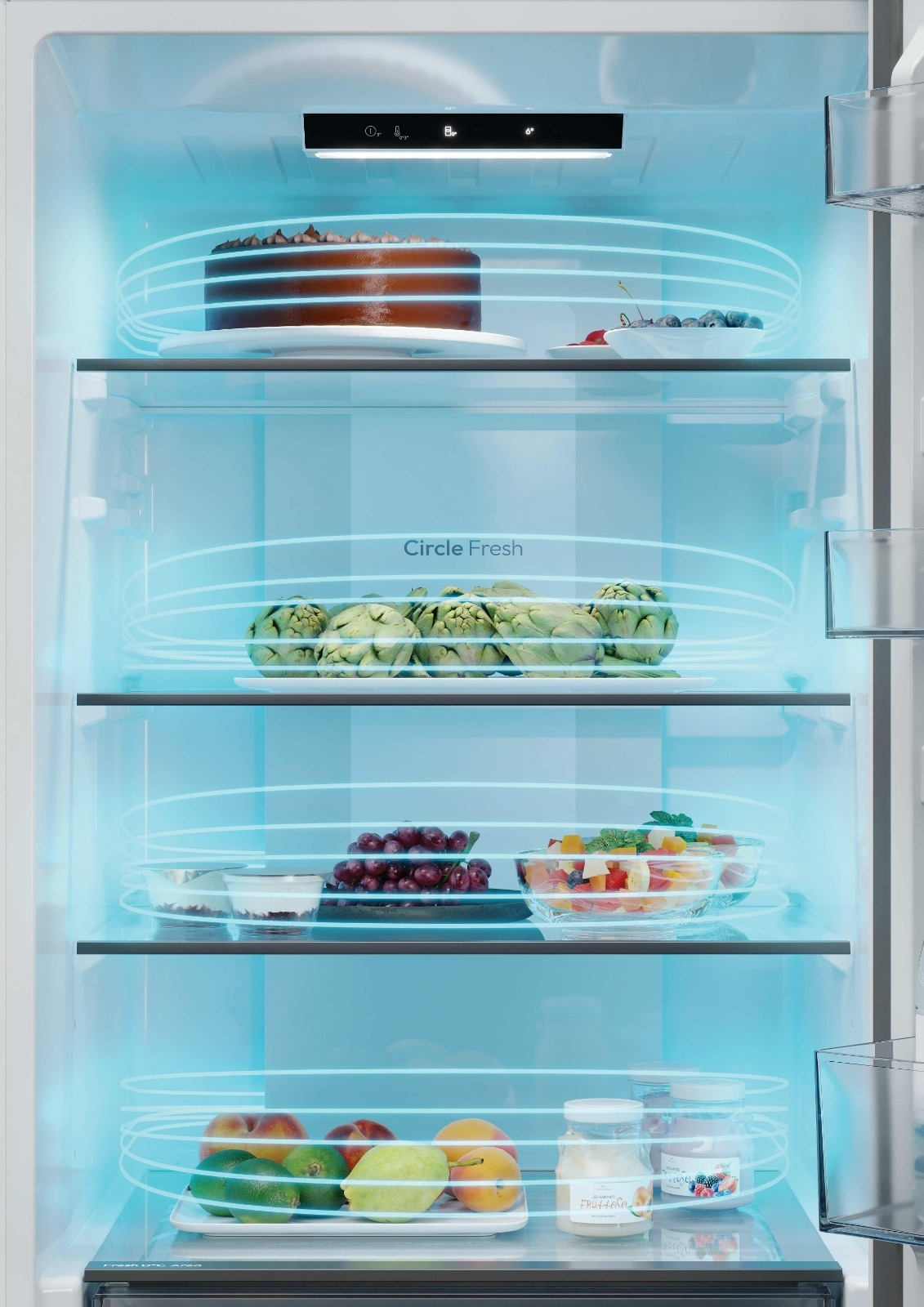 Frigorifero aperto con illuminazione blu, pieno di frutta fresca, verdura, una torta e yogurt.