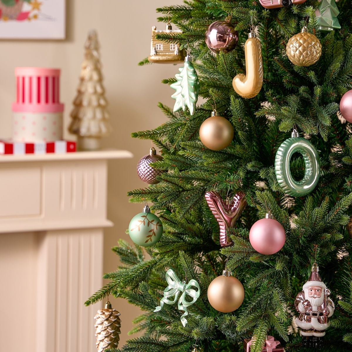 Un sapin de Noël décoré de divers ornements pastel brillants, avec une cheminée en arrière-plan.