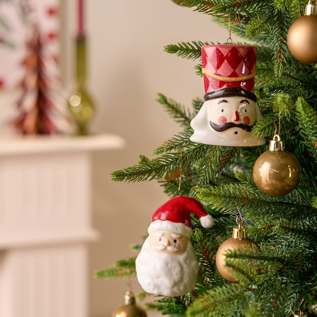 Un sapin de Noël décoré d'un casse-noisette, du Père Noël et de boules dorées sur fond flou.