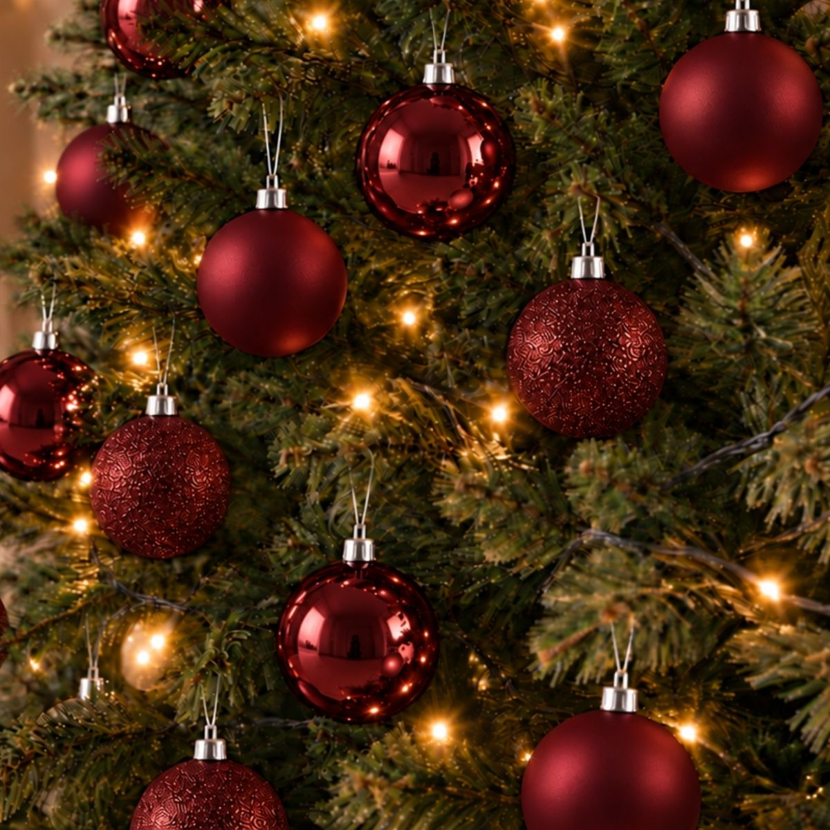 Un sapin de Noël décoré de boules rouges brillantes et de guirlandes lumineuses.