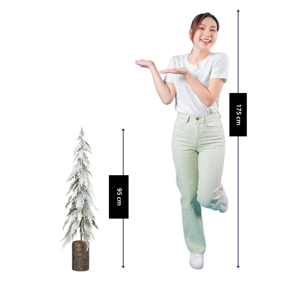 Une femme en t-shirt blanc et pantalon vert présente un sapin de Noël de 95 cm, contrastant avec sa hauteur de 175 cm.