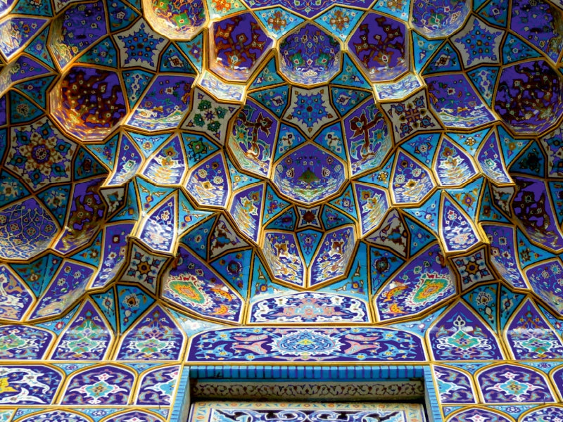 Komplexe blau-violett-goldene Mosaikfliesen an einer Gewölbedecke.