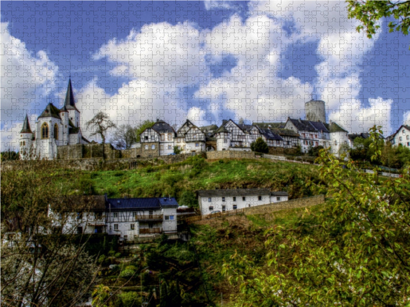 Ein malerisches deutsches Dorf auf einem grünen Hügel mit Fachwerkhäusern, einer Kirche und bewölktem Himmel.
