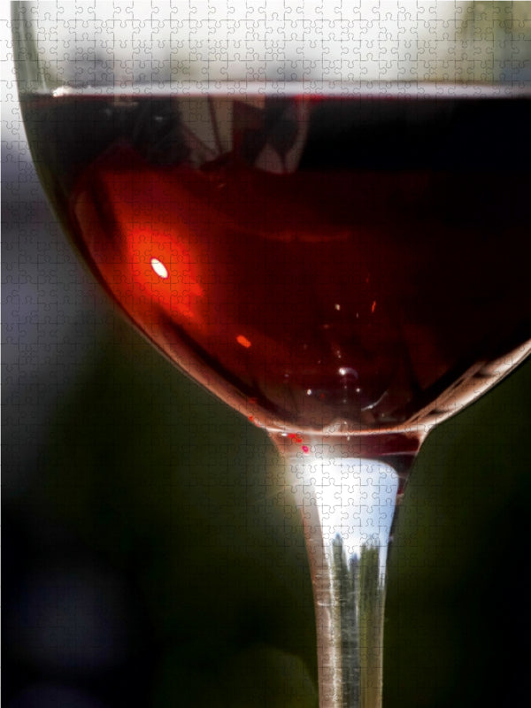 Ein Glas roter Wein mit glänzender Oberfläche in Nahaufnahme vor dunklem Hintergrund.