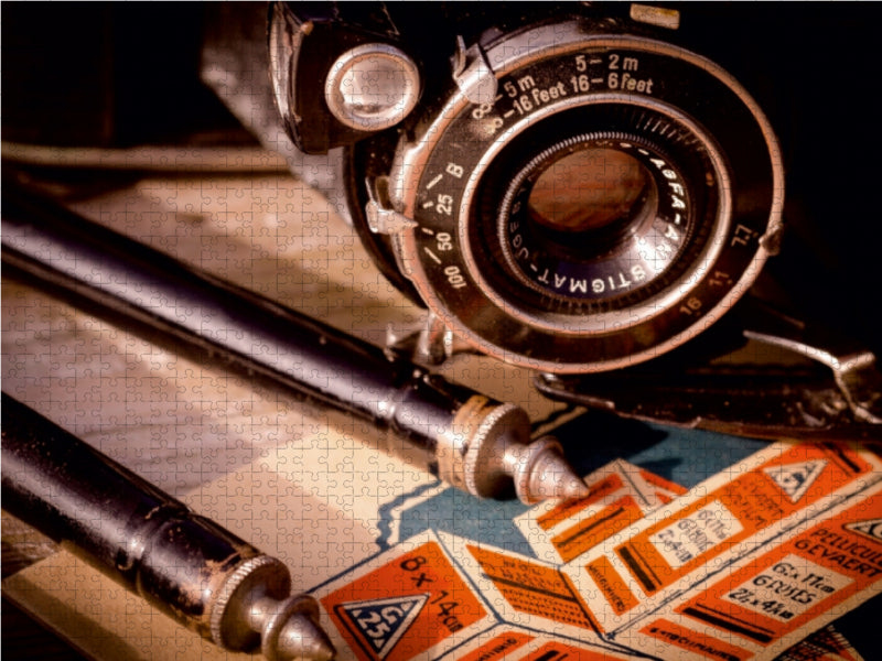 Eine alte Kamera und Vintage-Fotoausrüstung mit orangefarbener Verpackung liegen auf einer Holzoberfläche.