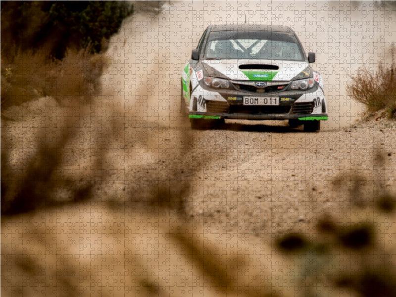 Ein Rallye-Auto fährt auf einer staubigen Schotterstraße und wirbelt Staub auf.