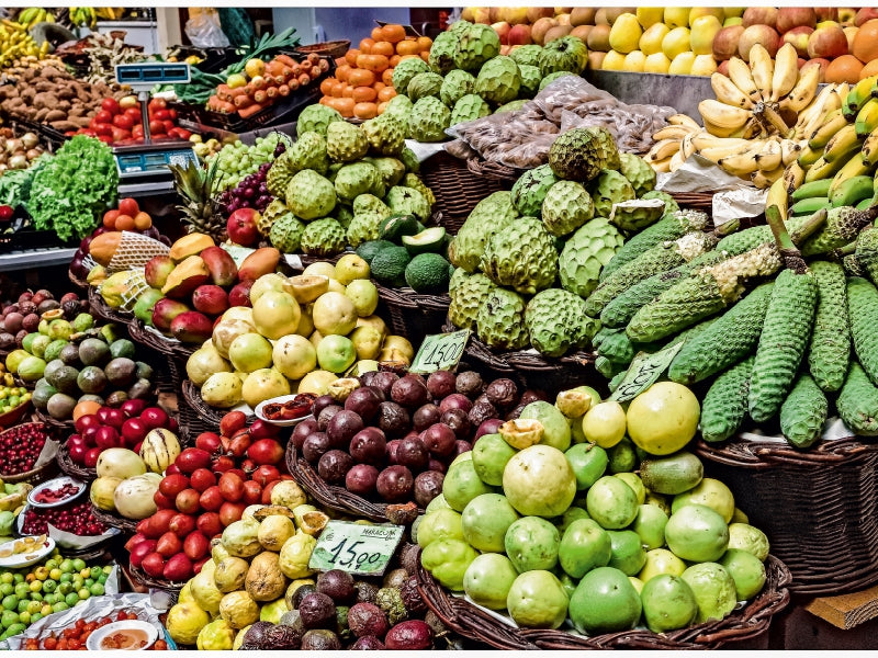 Marktstand mit bunten Früchten wie Bananen, Cherimoyas, Äpfeln und Passionsfrüchten.