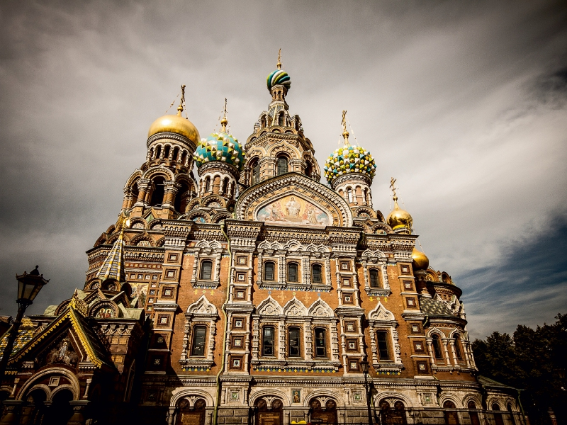 Die farbenfrohe Außenseite der Auferstehungskirche in Sankt Petersburg unter einem bewölkten Himmel.