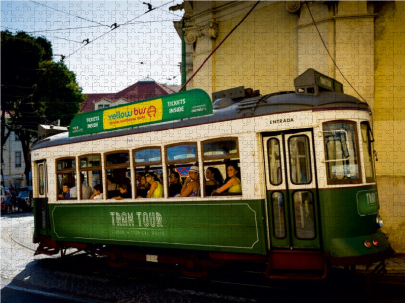 Eine historische grüne und weiße Straßenbahn voller Passagiere fährt auf einer Straße.