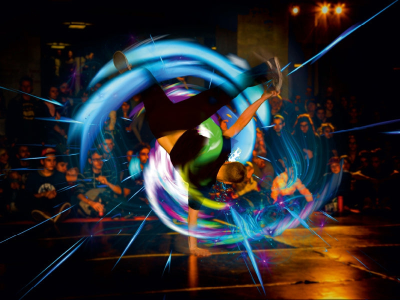Breakdancer macht einen Handstand auf der Bühne, umgeben von blauen Lichteffekten und schauendem Publikum.