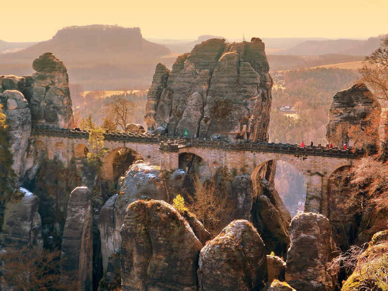 Bastei-Brücke in felsiger Landschaft bei Sonnenuntergang.