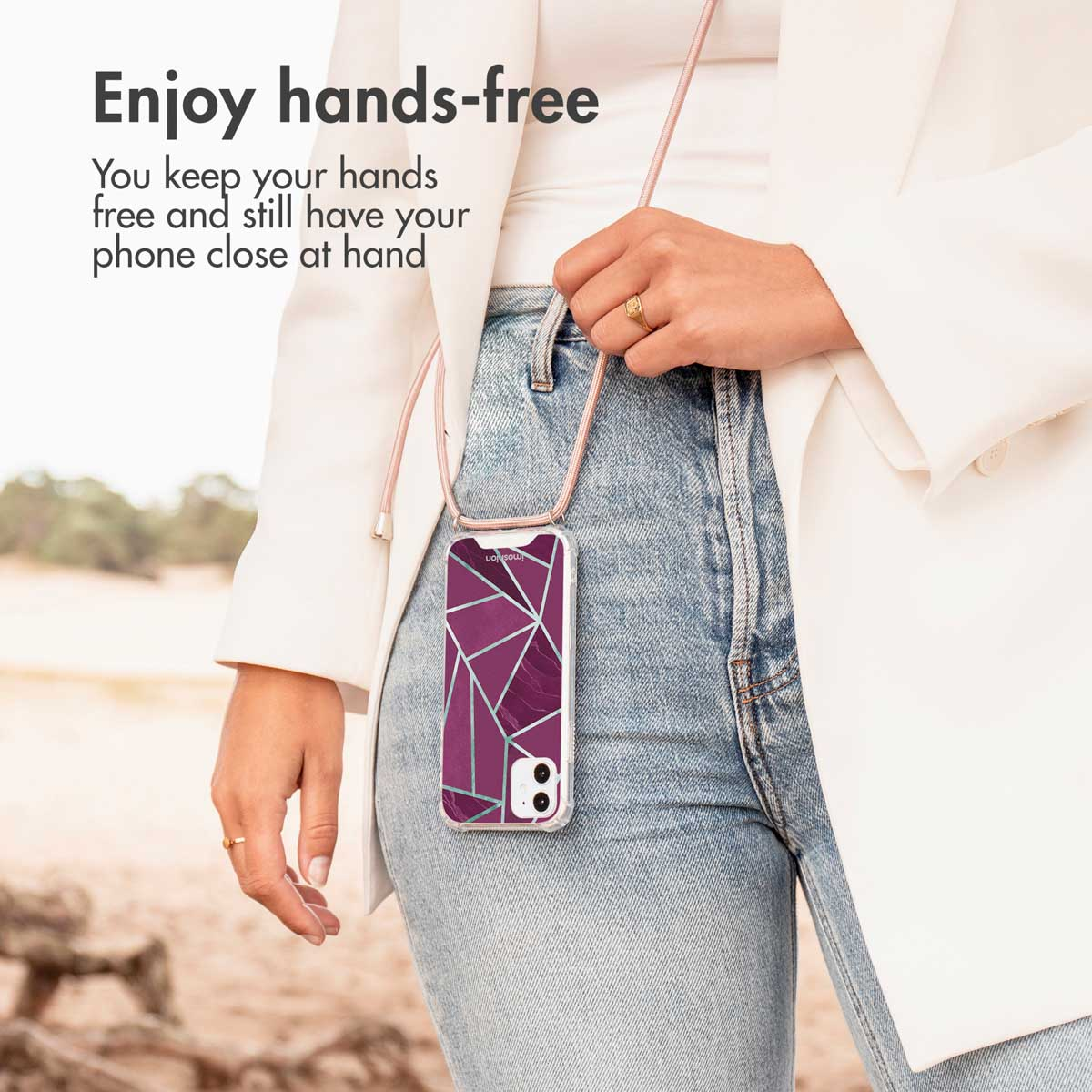 Una mujer lleva un teléfono con funda geométrica morada y correa al cuello, con texto y playa de fondo.