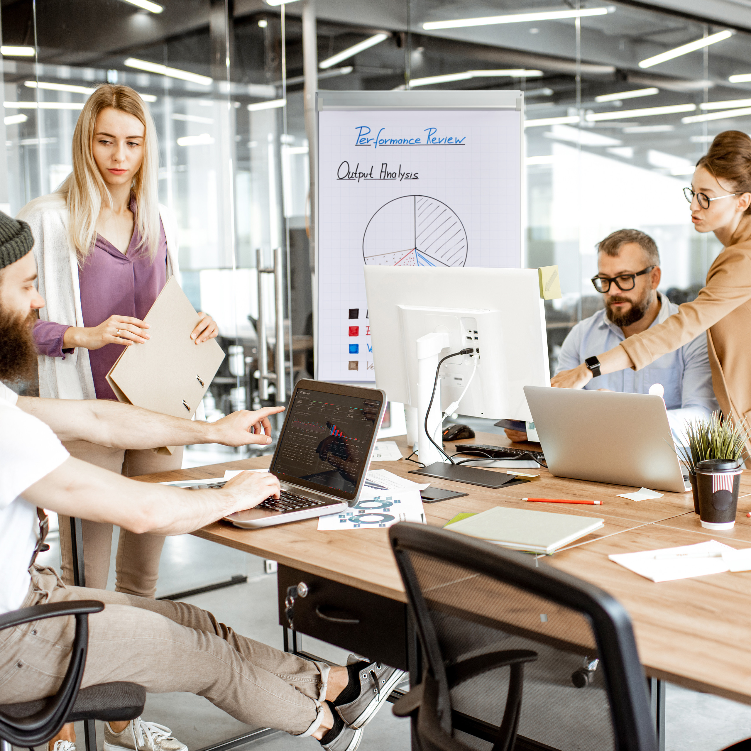 Ein Team von Fachleuten arbeitet an einem Tisch in einem modernen Büro mit Laptops und Diagrammen.