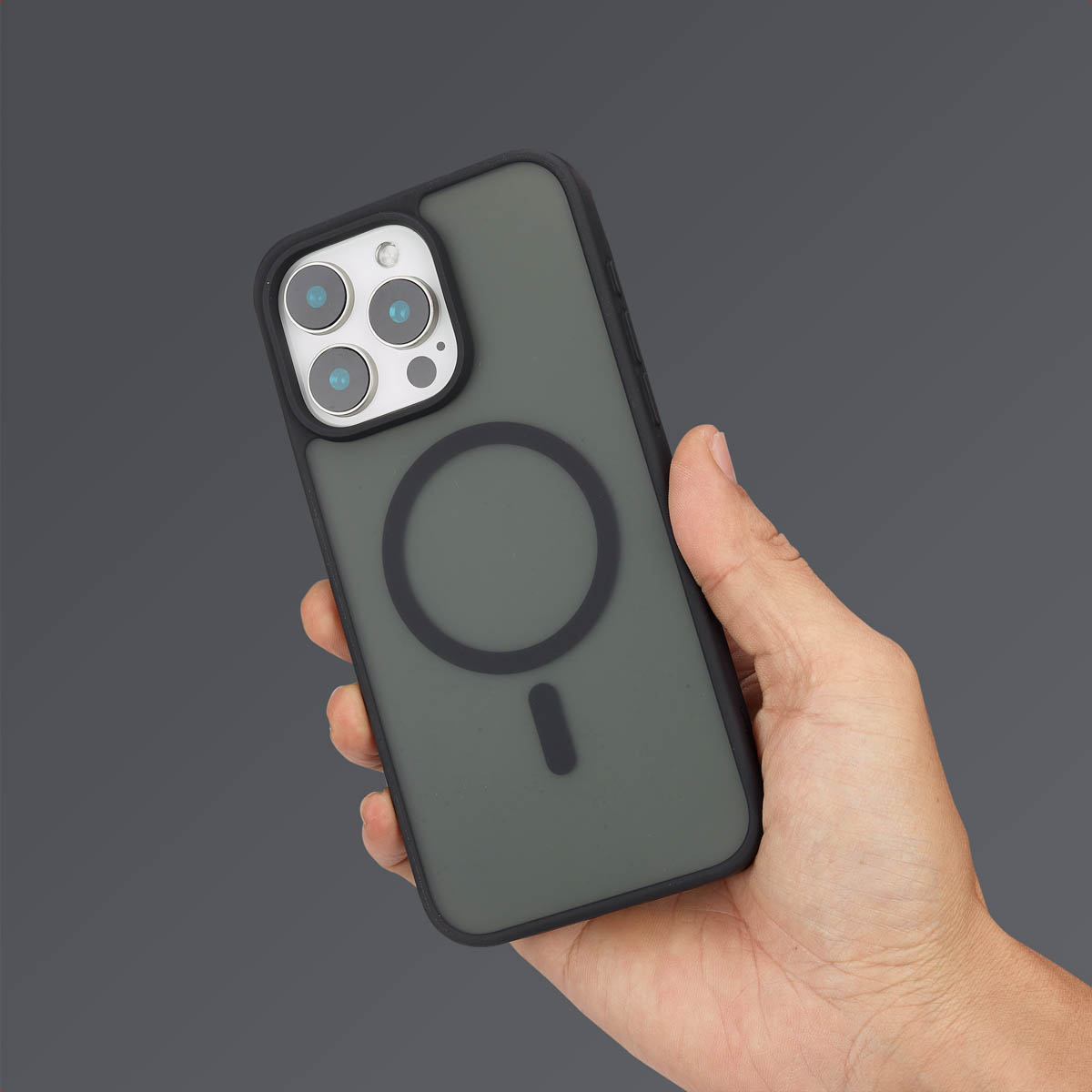 Une main tient un smartphone sombre dans une coque mate avec anneau.