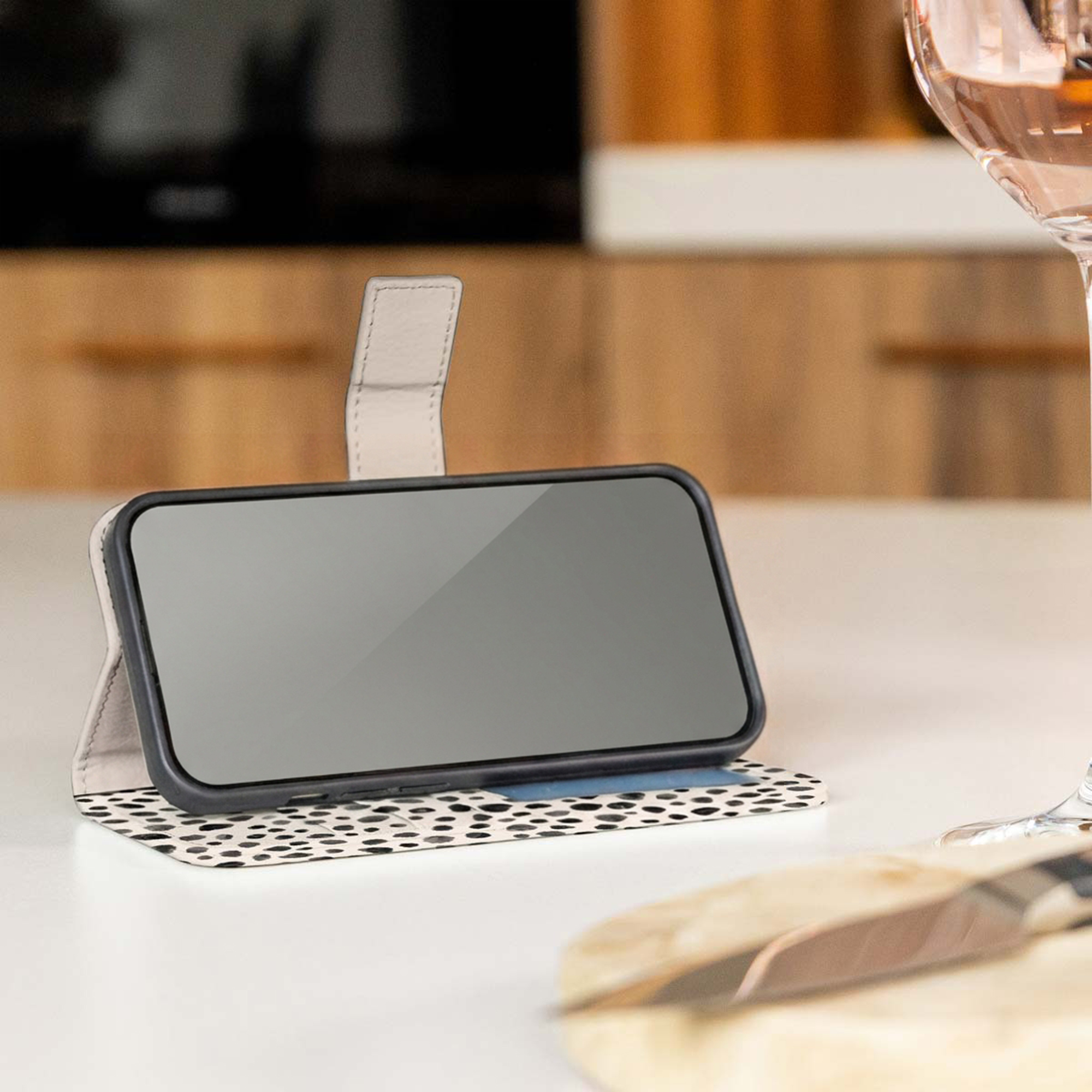 Smartphone en funda con estampado dálmata blanco y negro sobre mesa clara.