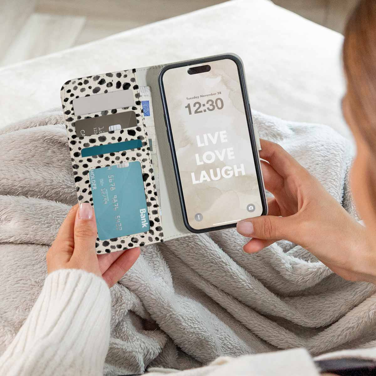 Persona sosteniendo una funda de móvil con tarjetero de lunares blancos y negros.