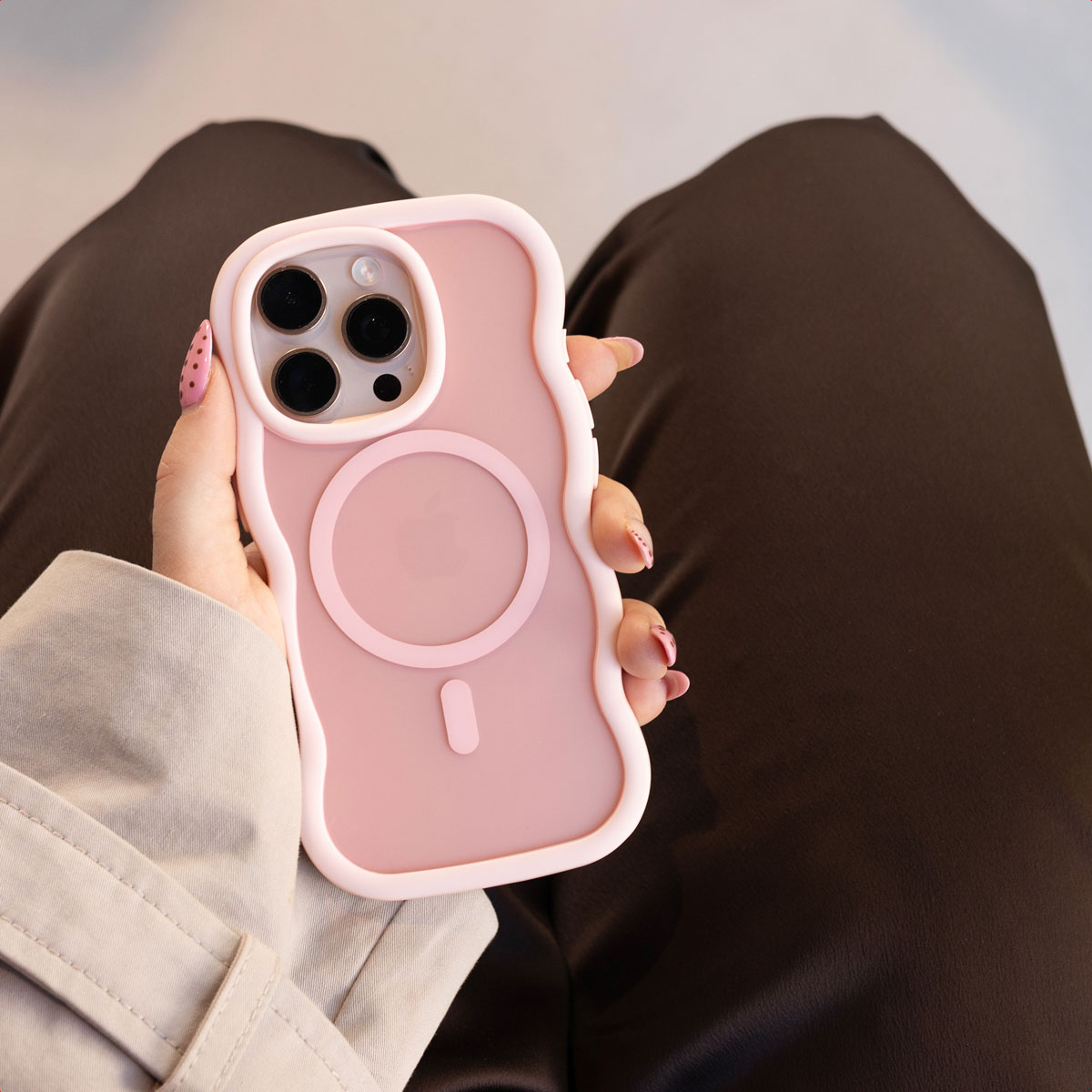 Main tenant un smartphone rose dans une coque ondulée avec cercle MagSafe.