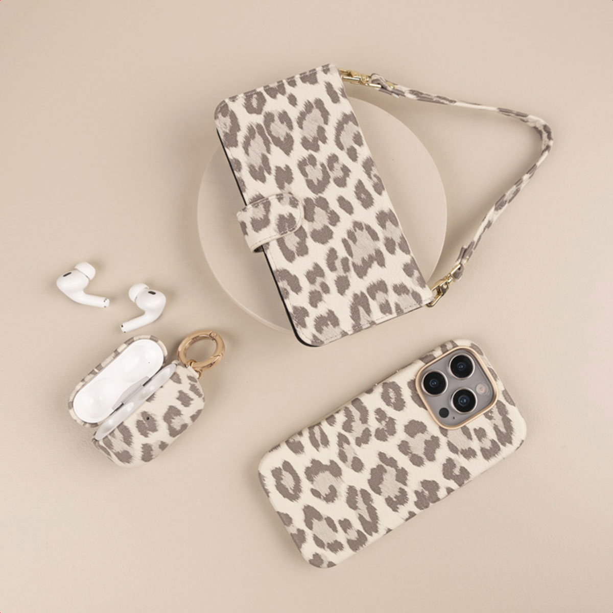 Custodia per telefono, astuccio e auricolari leopardati su fondo beige.