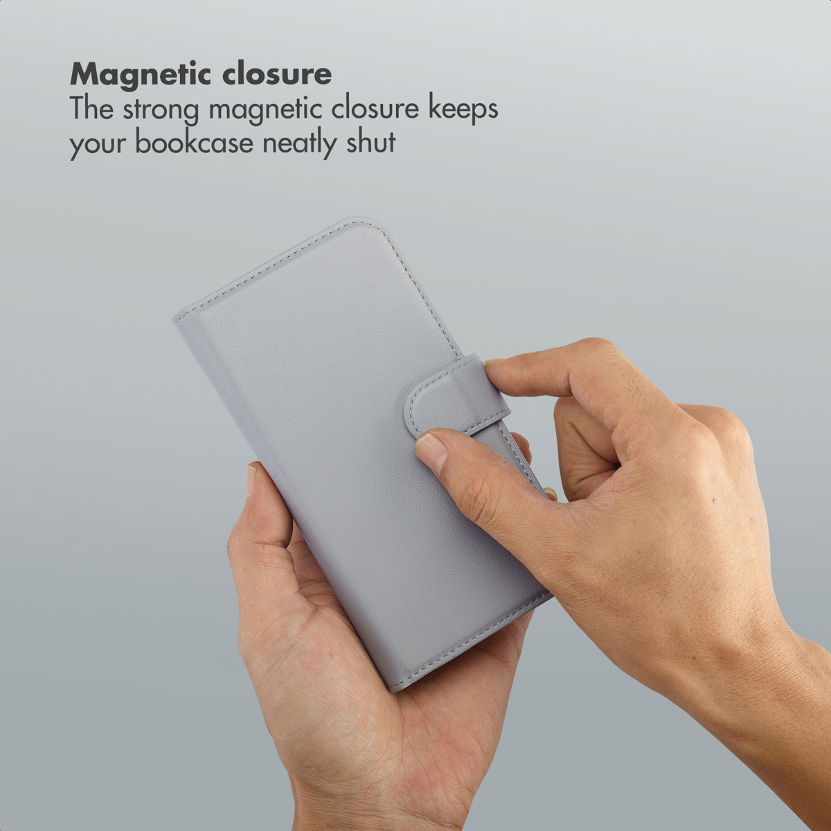 Una funda tipo libro gris es sostenida por manos, mostrando el cierre magnético.