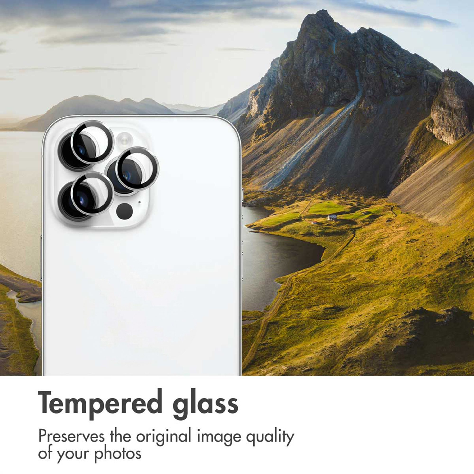 Een witte smartphone met gehard glas lensbeschermers tegen een achtergrond van bergen en een meer.