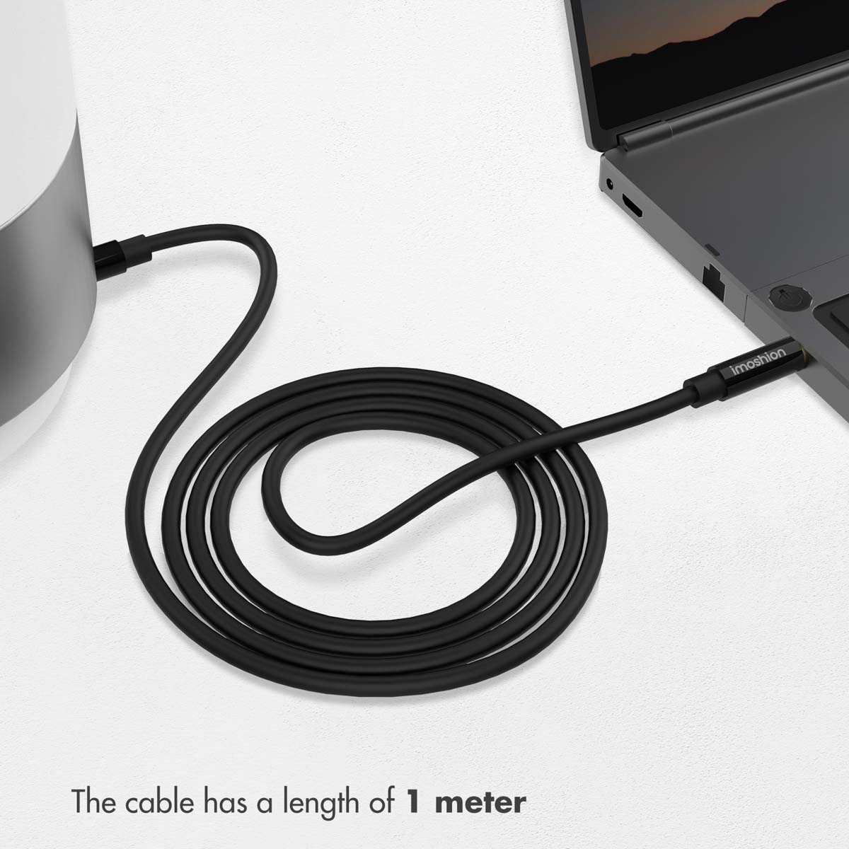 Een lange zwarte kabel verbindt een wit object met een grijze laptop op een witte achtergrond.