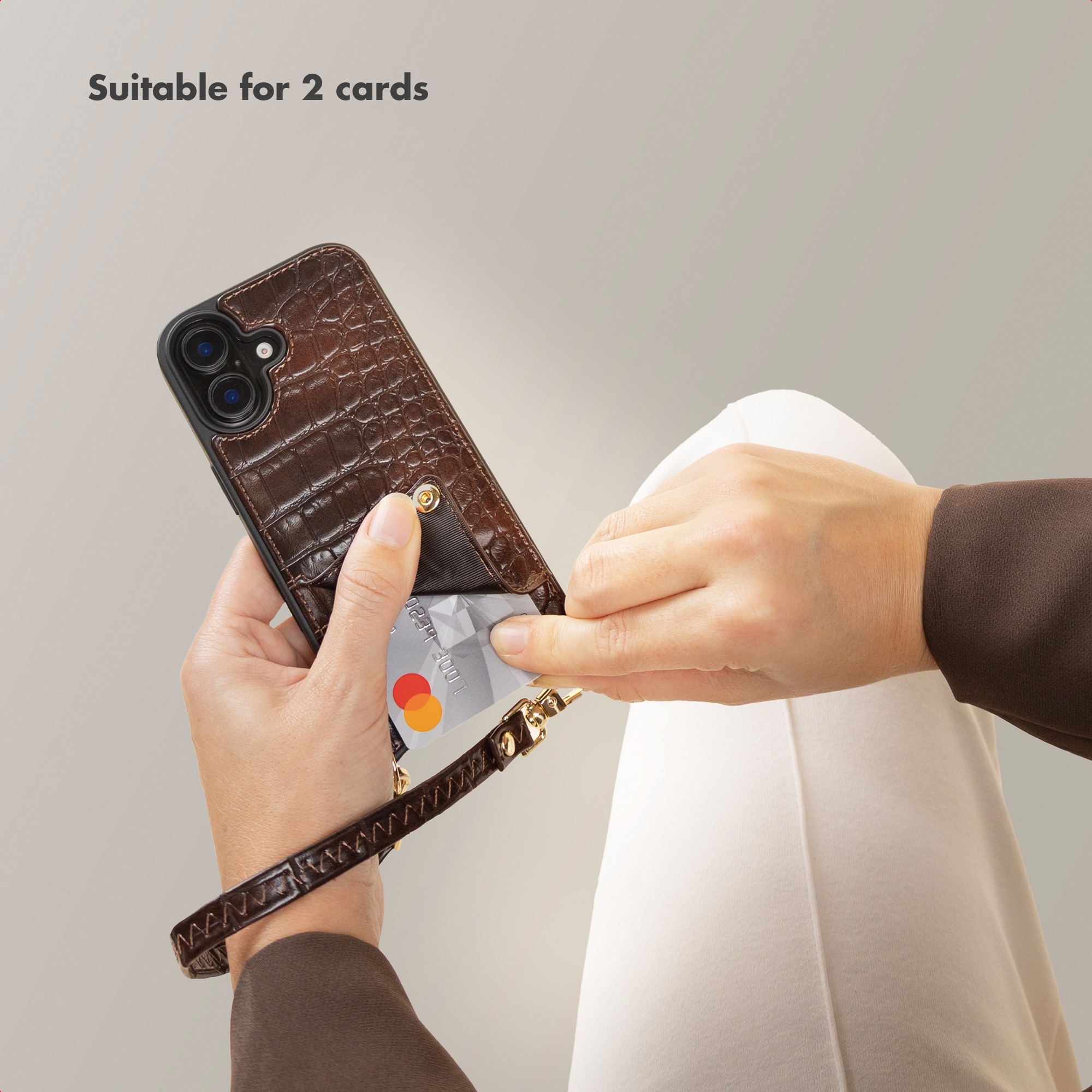 Persona sosteniendo una funda de teléfono de cuero marrón de cocodrilo con una tarjeta de crédito y una correa.
