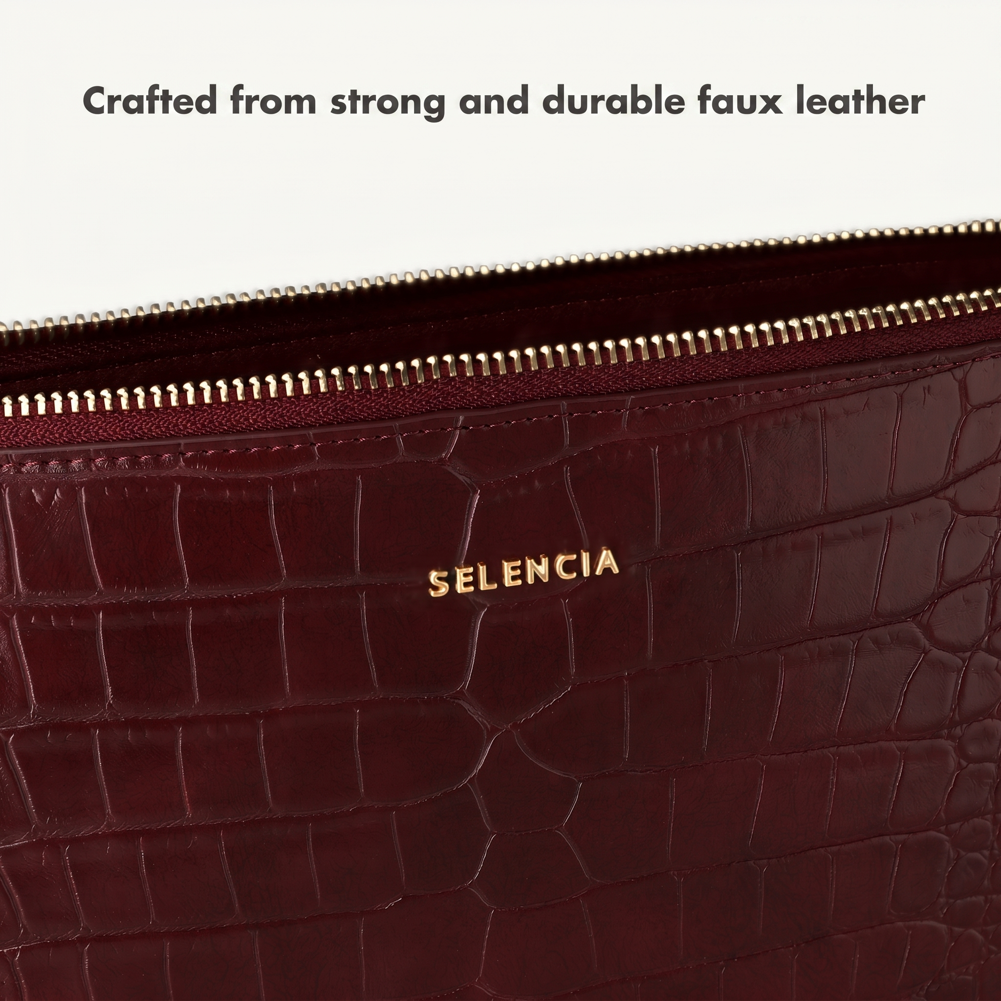 Primo piano di una borsa in ecopelle rosso scuro con cerniera dorata e il marchio SELENCIA.