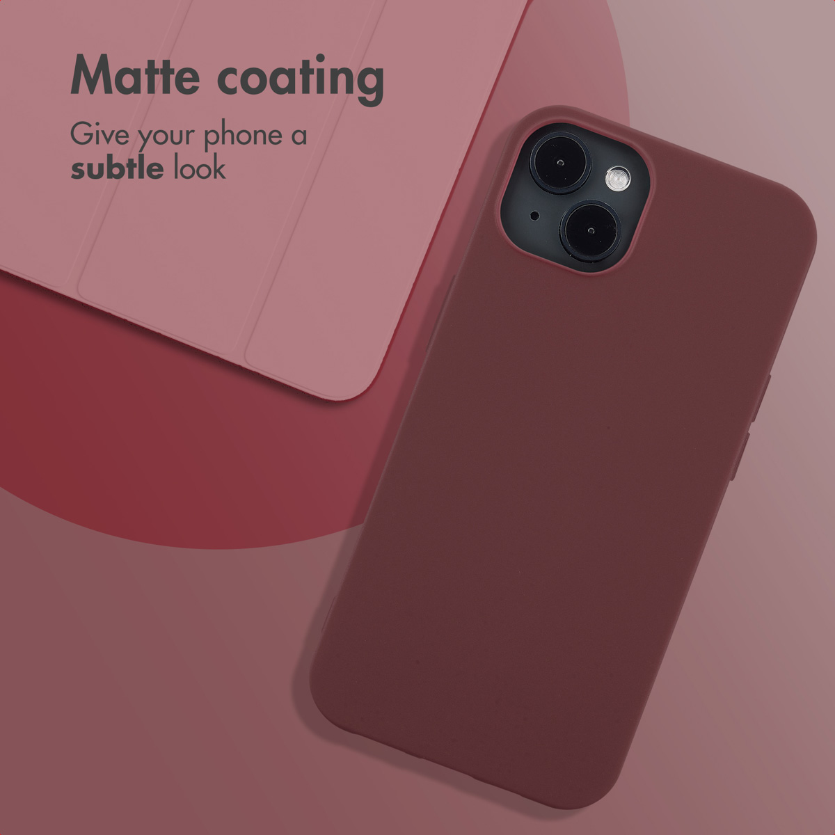 Matowe, ciemnoczerwone etui na smartfon leży na różowej powierzchni obok pasującego pokrowca.