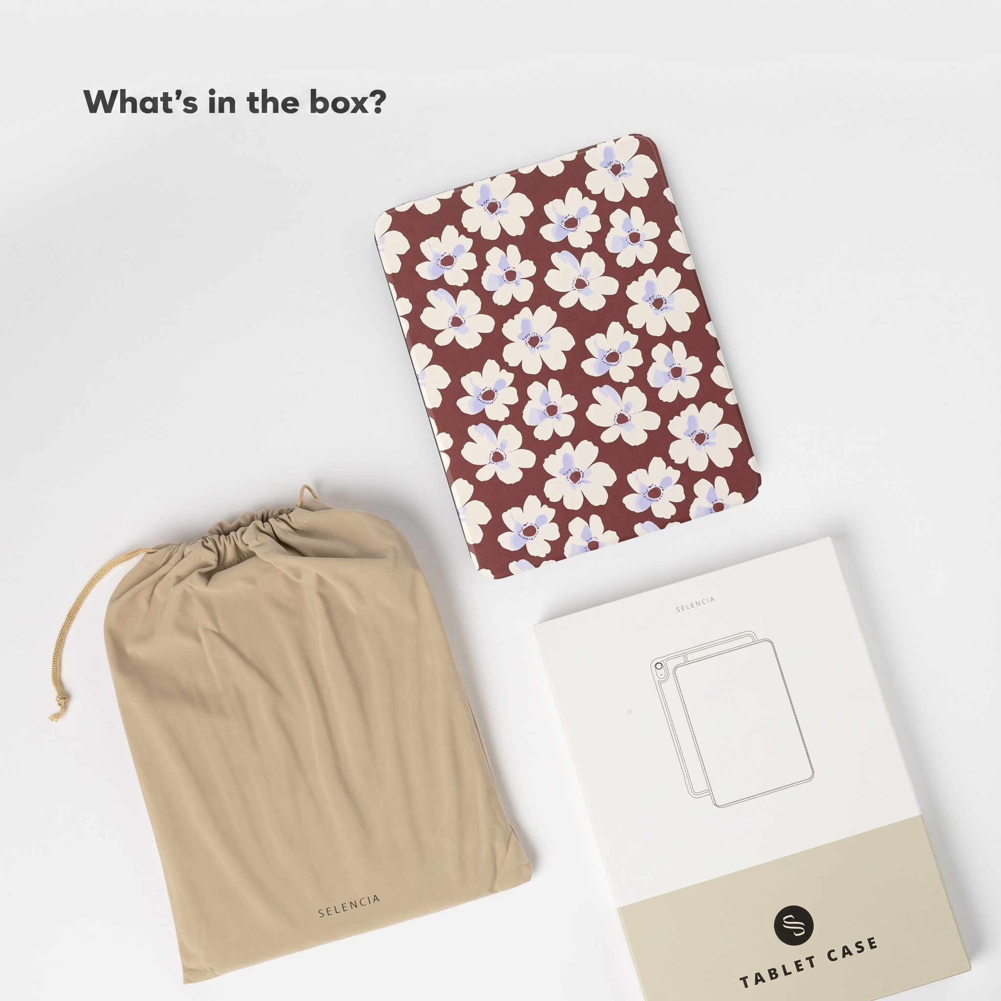 Een platte weergave met een rode tablethoes met witte bloemen, een beige zakje en een Selencia-doos.